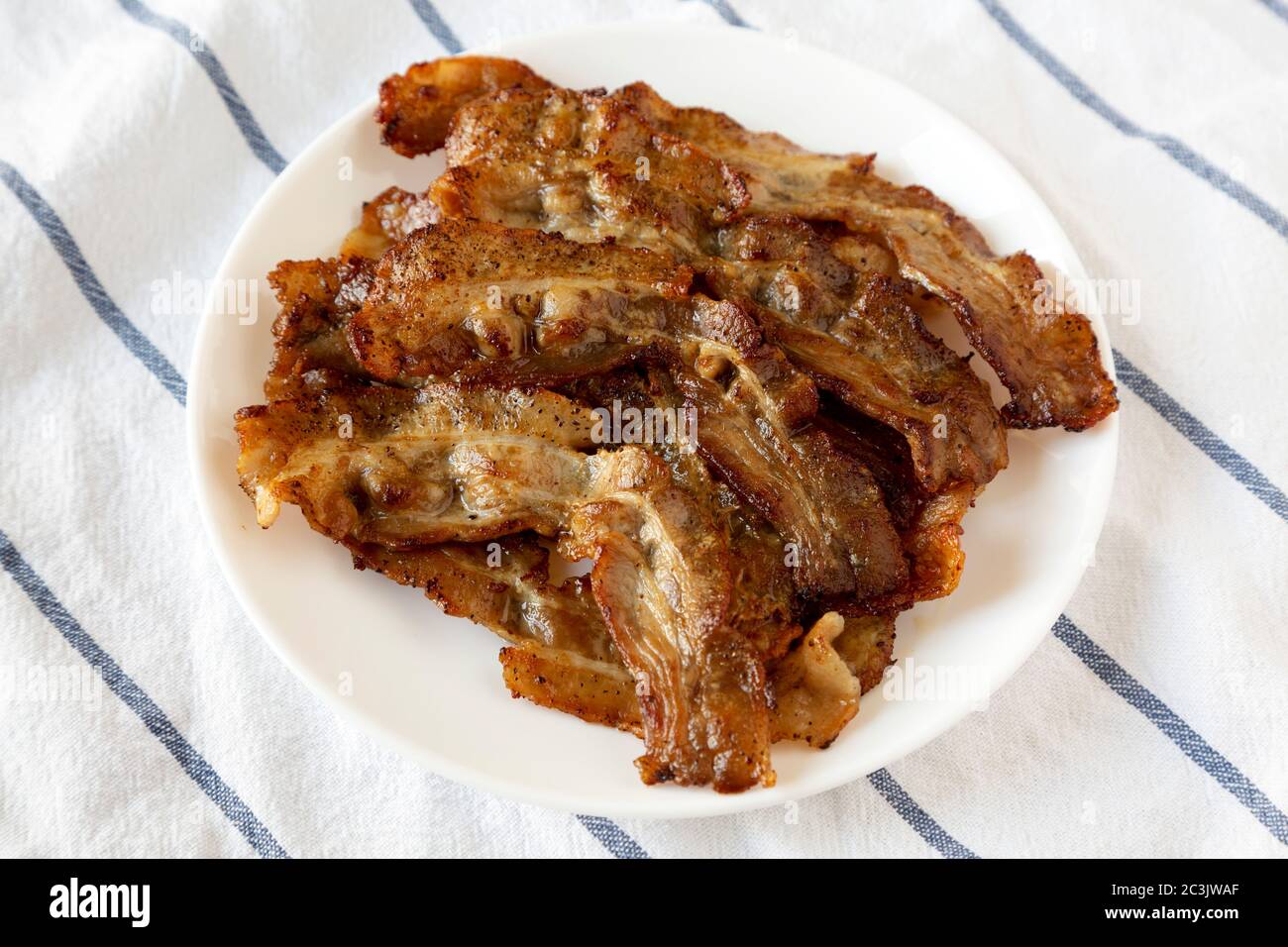 A close up view of bacon sizzling in the frying pan on a stovetop. Cooking  bacon slices for breakfast fry up Stock Photo - Alamy