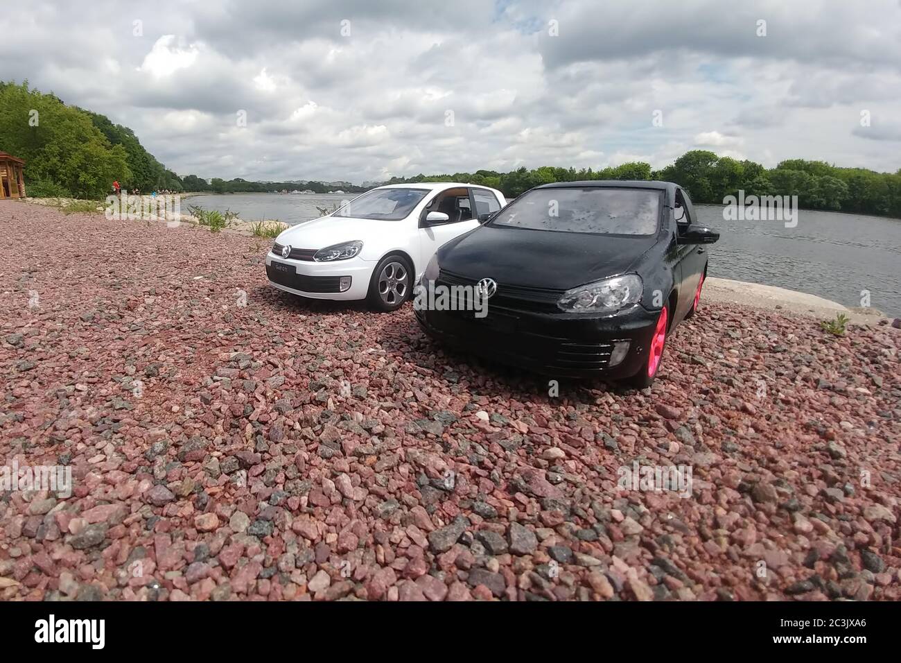 Moscow, Russia - May 03, 2019: Two toy cars in river park. 2 Volkswagen golf mk6 stand on a pebble beach. White and black GTI stand next to each other. Stock Photo