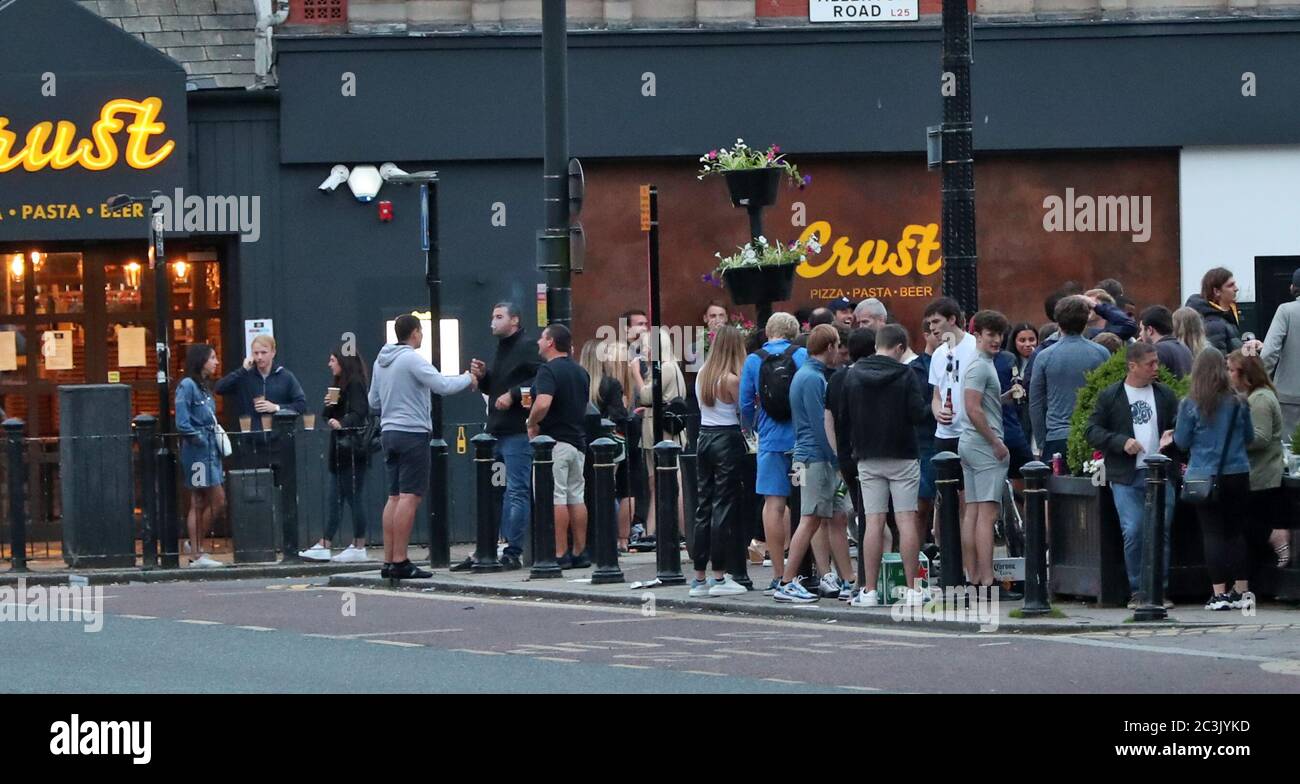 Crowds of people gather in Woolton Village, Liverpool and drink alcohol served from local food outlets as further coronavirus lockdown restrictions are lifted in England. Stock Photo