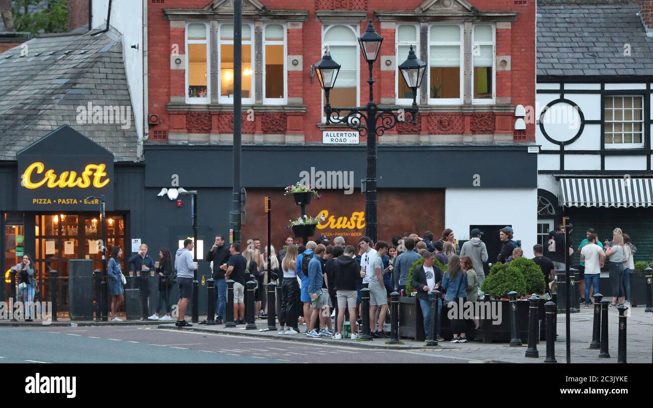 Crowds of people gather in Woolton Village, Liverpool and drink alcohol served from local food outlets as further coronavirus lockdown restrictions are lifted in England. Stock Photo
