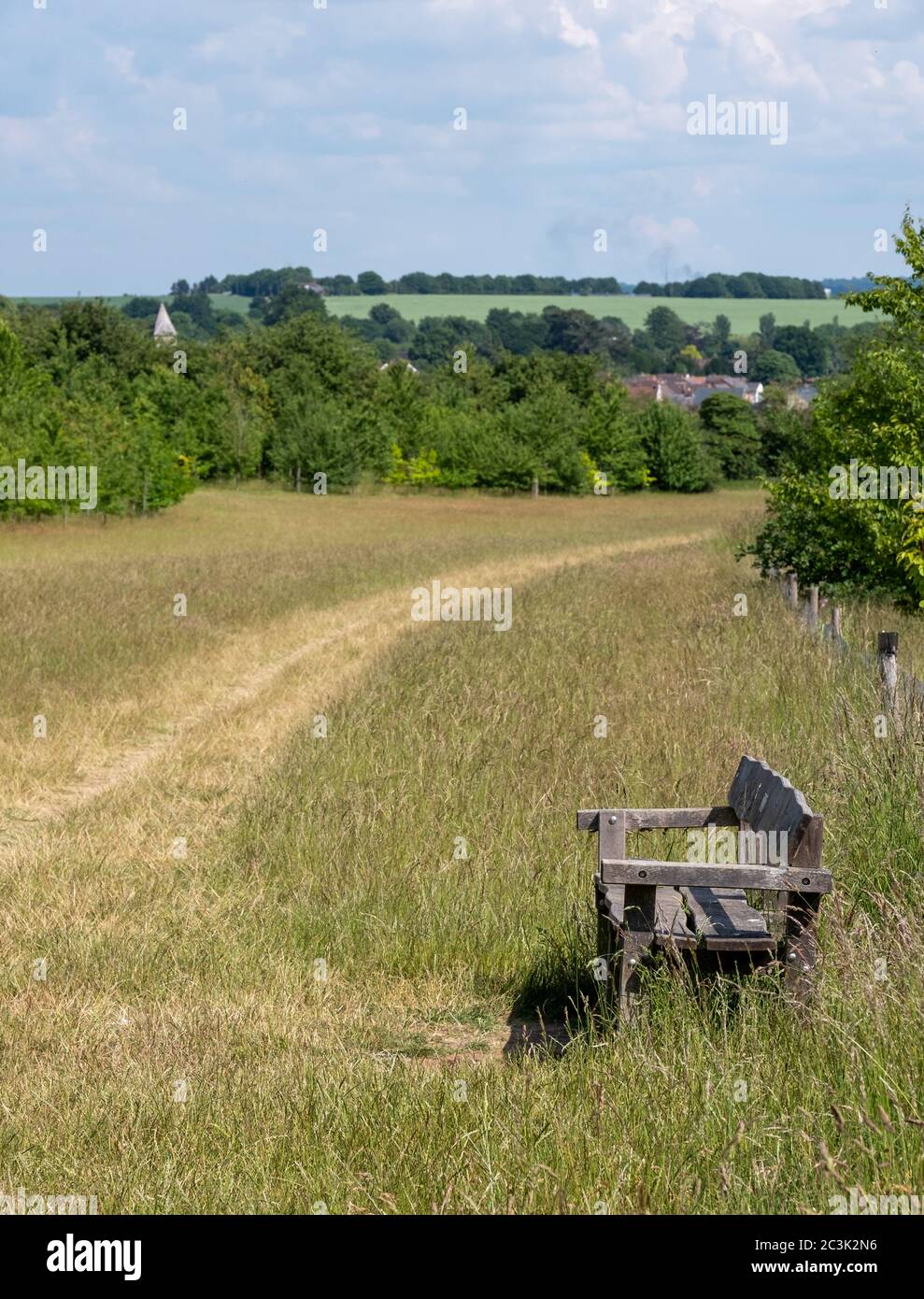 Village of Sandridge on the horizon, photographed with a wooden bench in the foreground from Heartwood Forest, near St Albans, Hertfordshire UK. Stock Photo