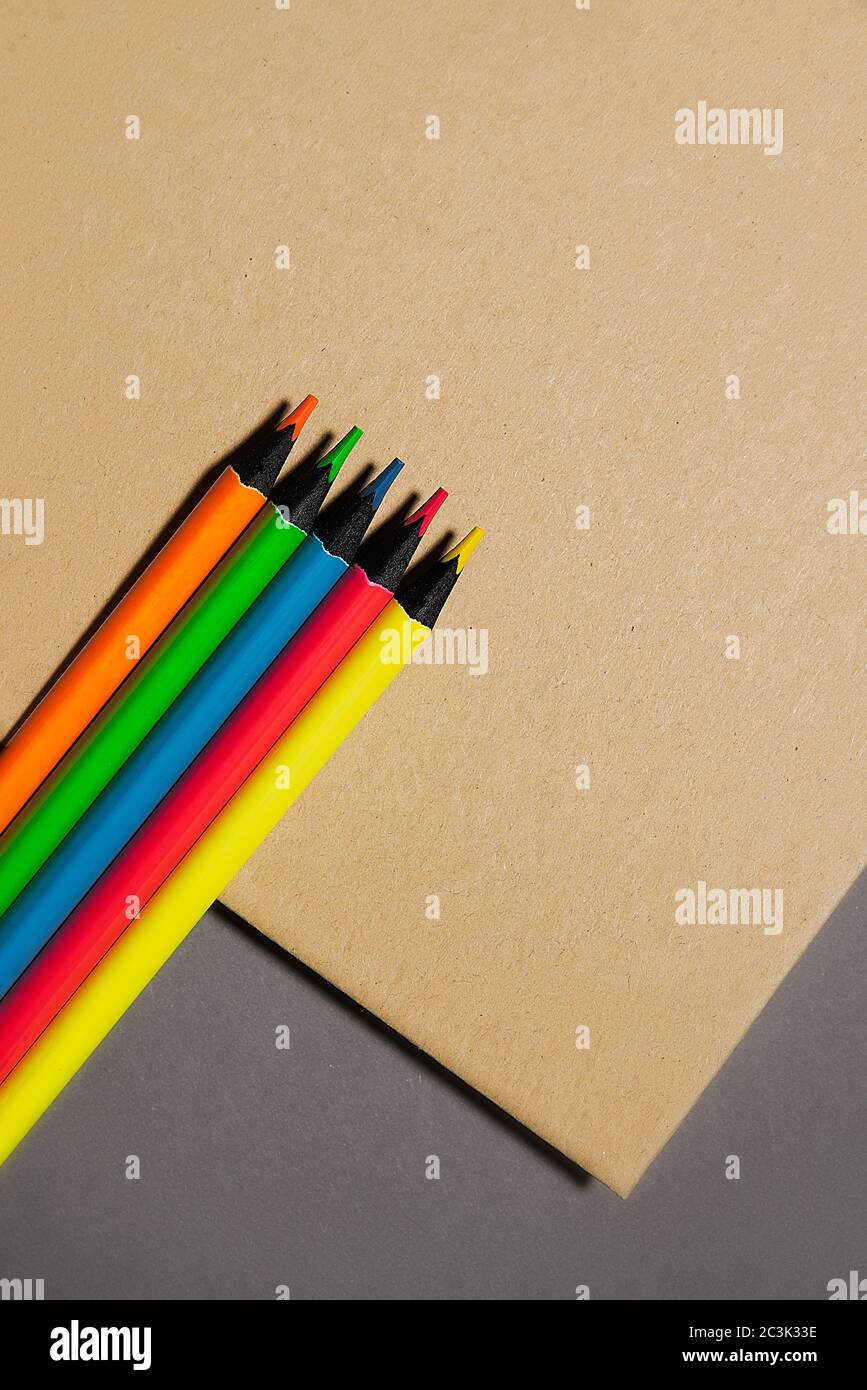 five colored pencils lie on  kraft notebook gray background, top view Stock Photo