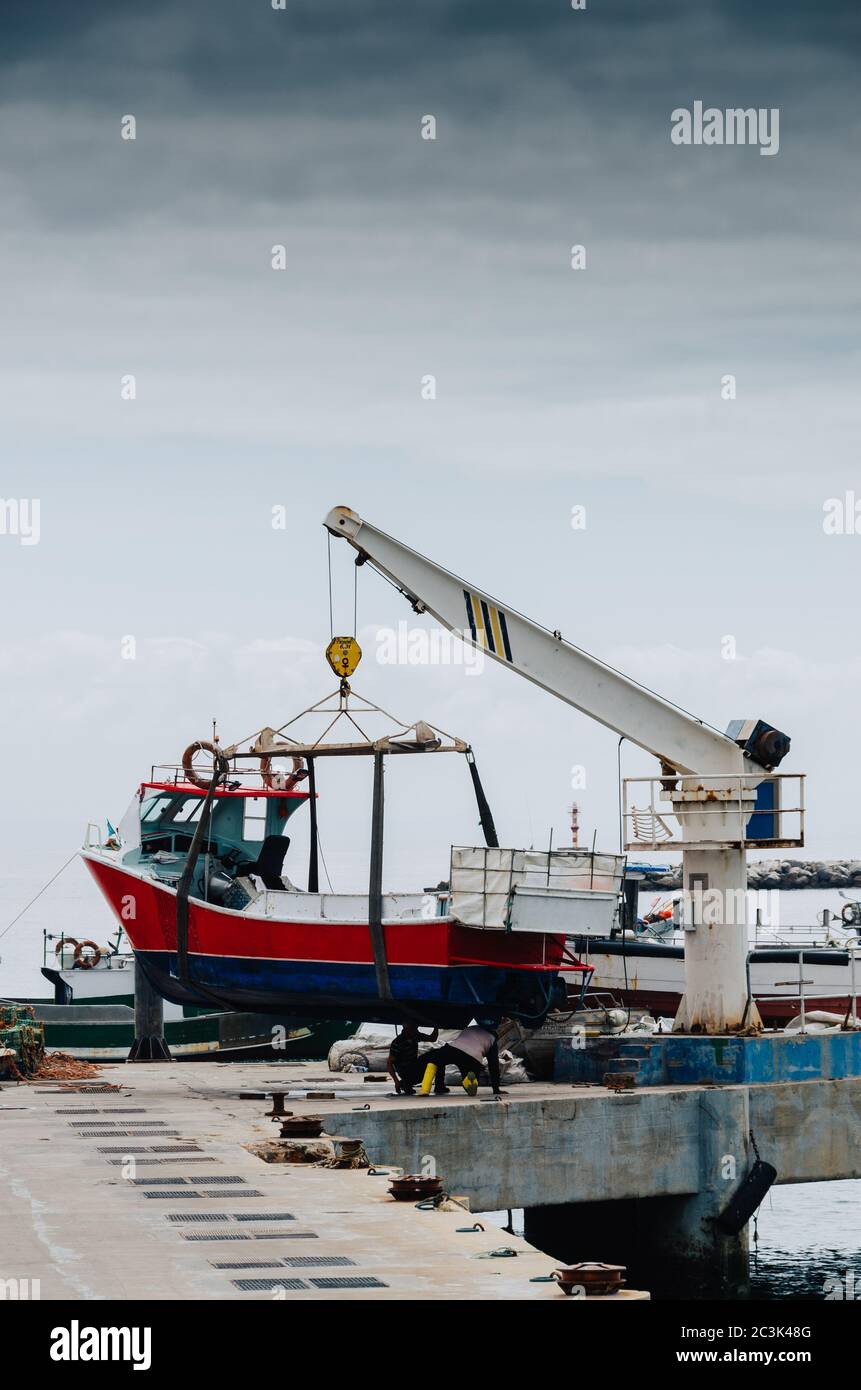 Vertical shot of a crane lifting a white boat on a pier Stock Photo - Alamy