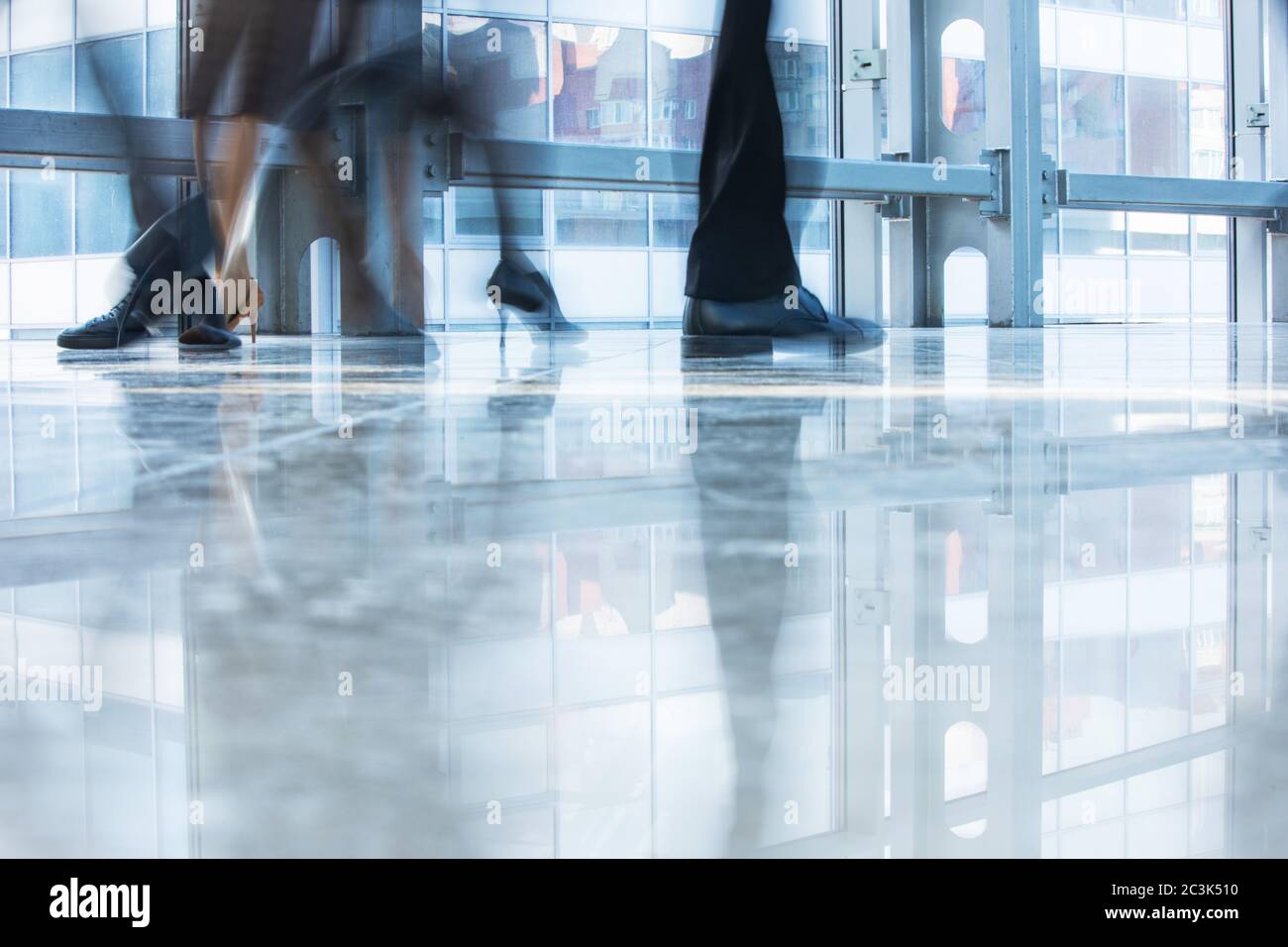 Blurred motion of business people walking inside modern office building wearing formal and high heel shoes of, business women, business man during rus Stock Photo