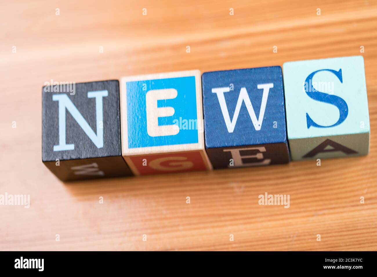 High angle shot of [NEWS] written with letter cubes on the table under the lights Stock Photo