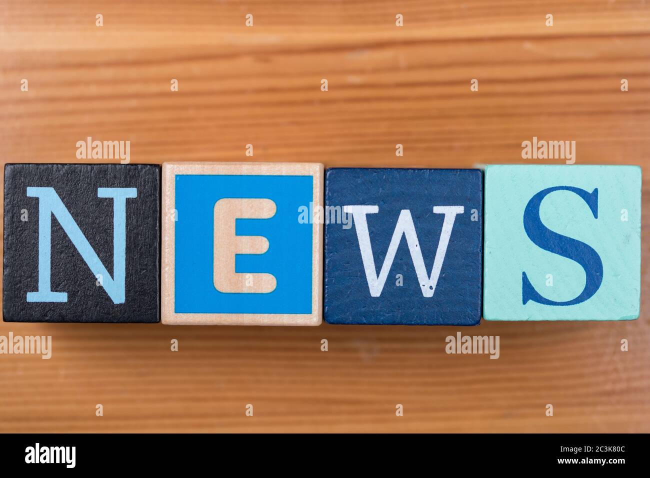 High angle shot of [NEWS] written with letter cubes on the table under the lights Stock Photo