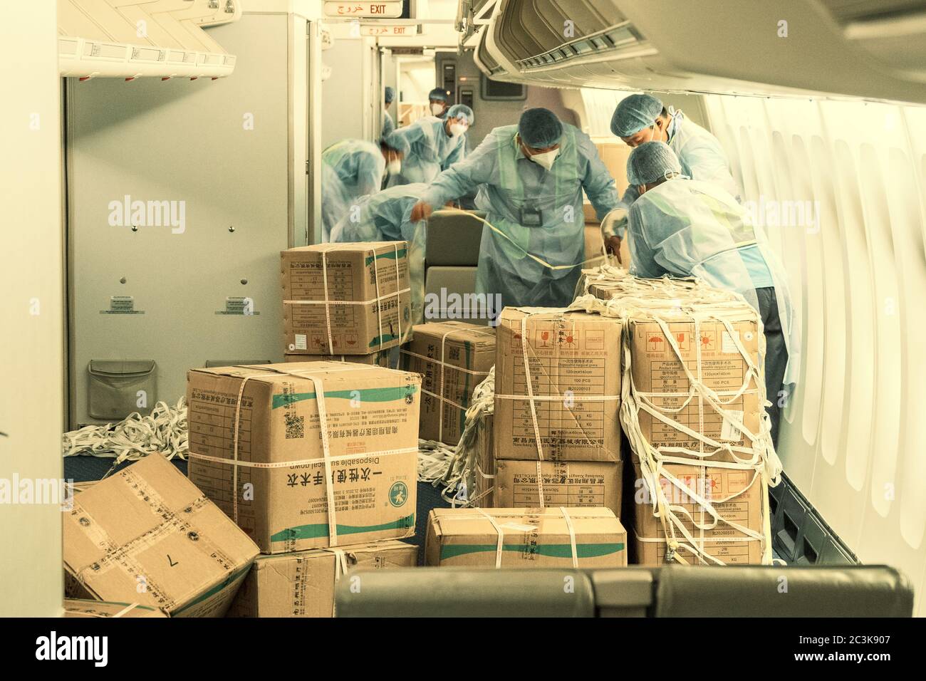 Chinese loaders wearing hazmat suits loading a converted passenger into freighter plane with surgical masks and gowns to fight the COVID pandemic Stock Photo