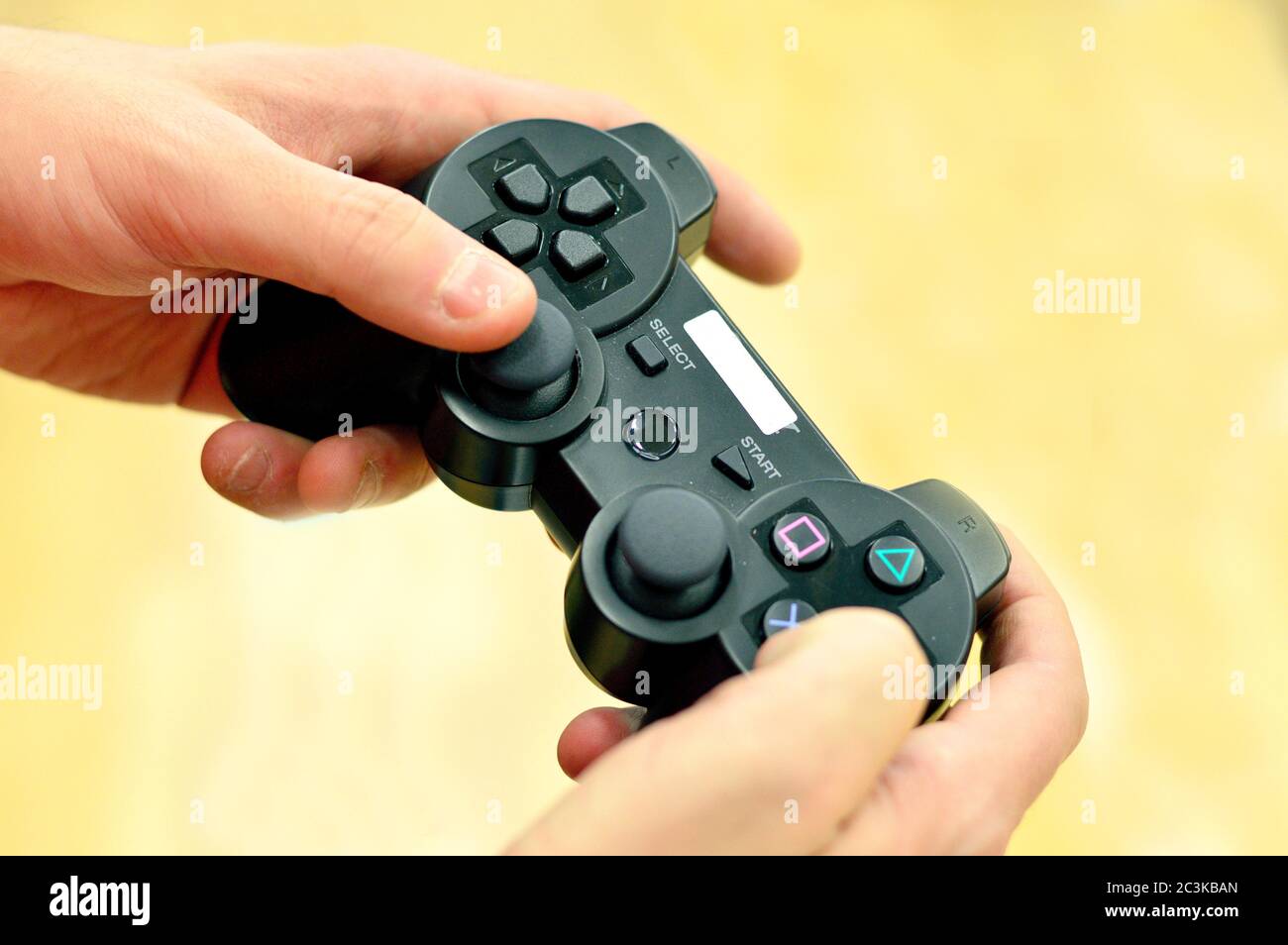 Man's Hands Holding Remote Controller against light background Stock Photo