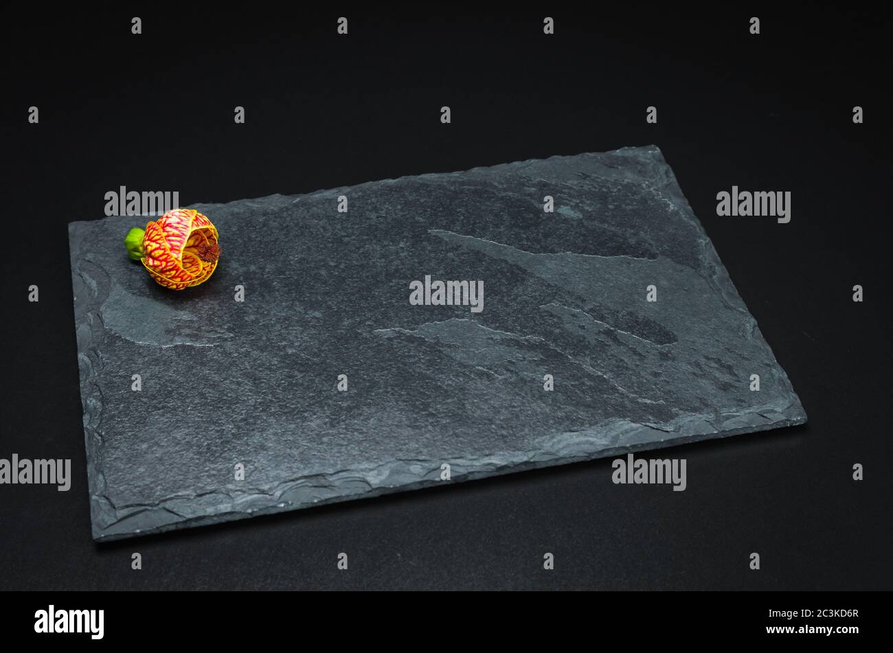 Empty slate plate on black background for use in culinary photos. Stock Photo