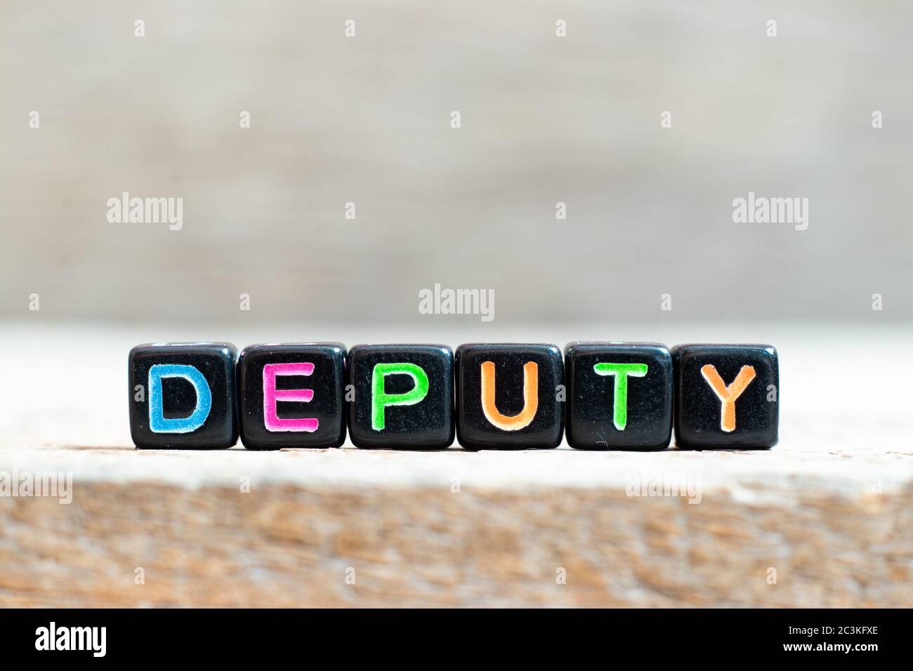 Black bead with color letter in word deputy on wood background Stock Photo