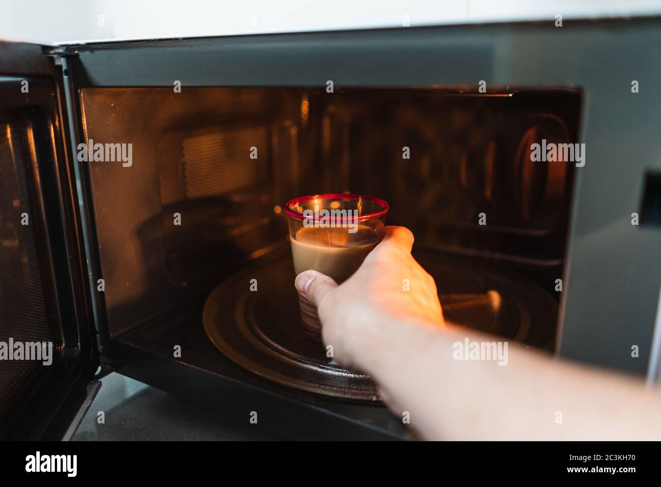 Closeup shot of a hand of the male putting a cup in the microwave to