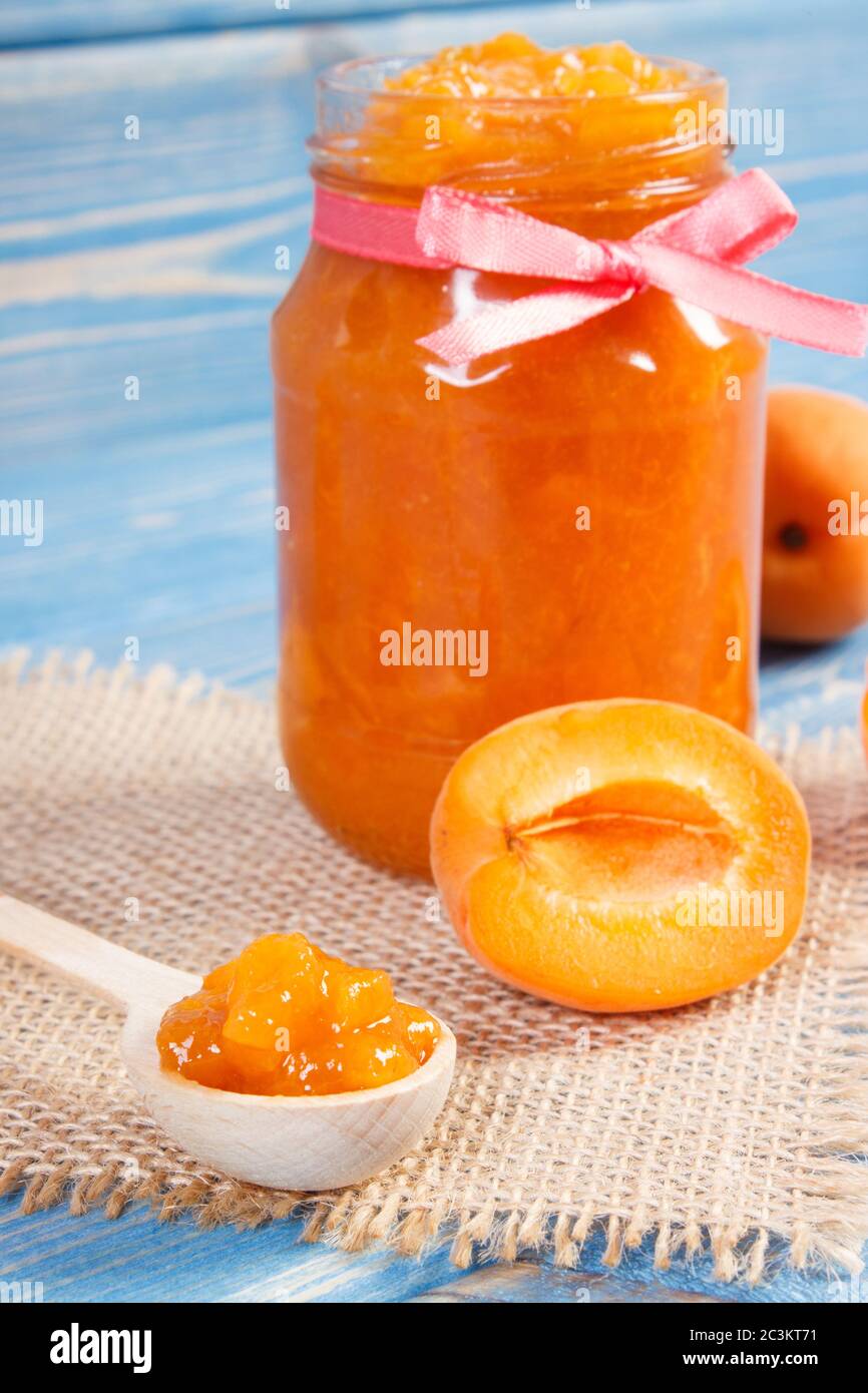 Fresh homemade apricot marmalade and ripe fruits on blue boards, concept of healthy sweet dessert Stock Photo