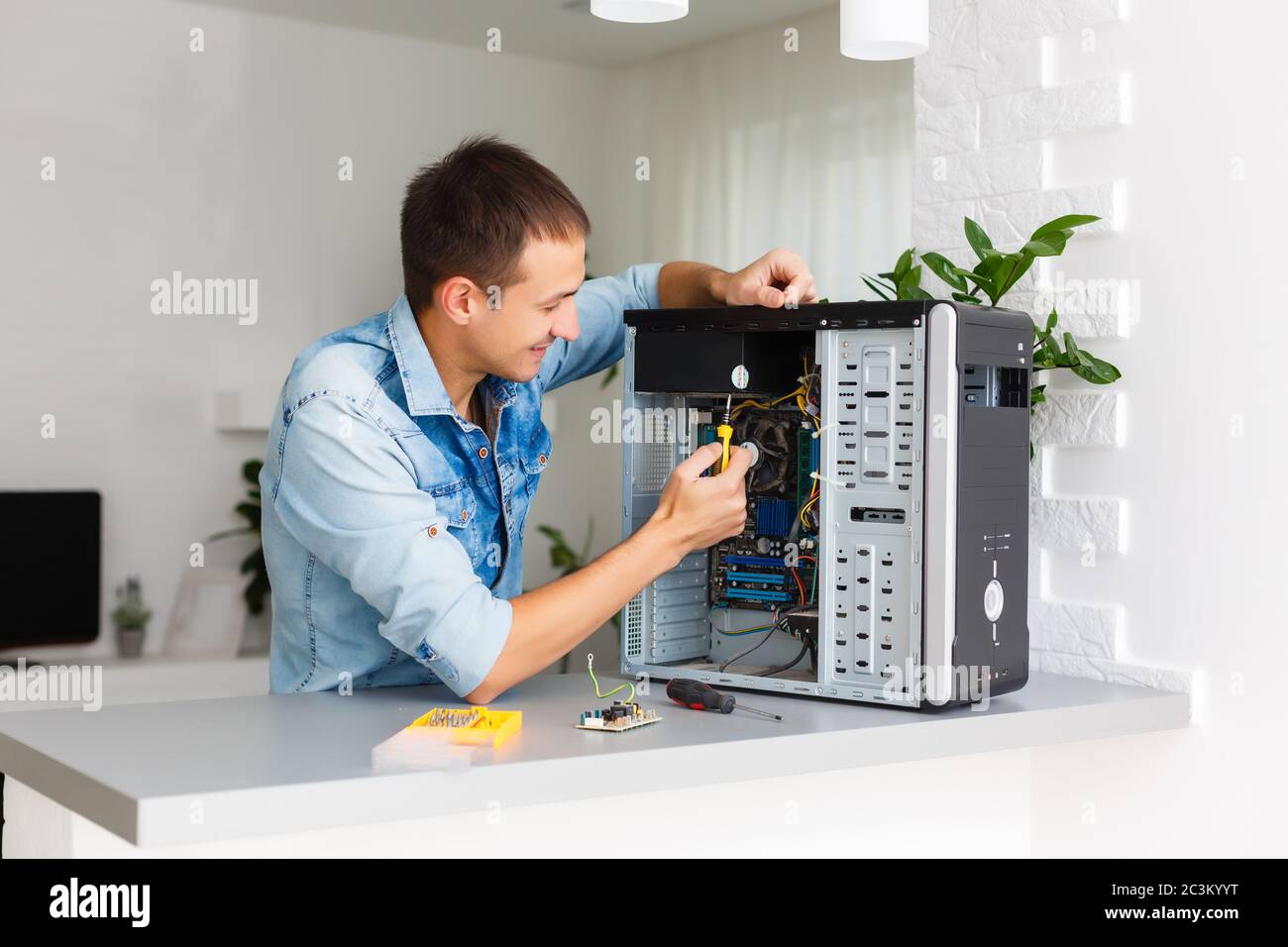 Young technician working on broken computer in his office Stock Photo
