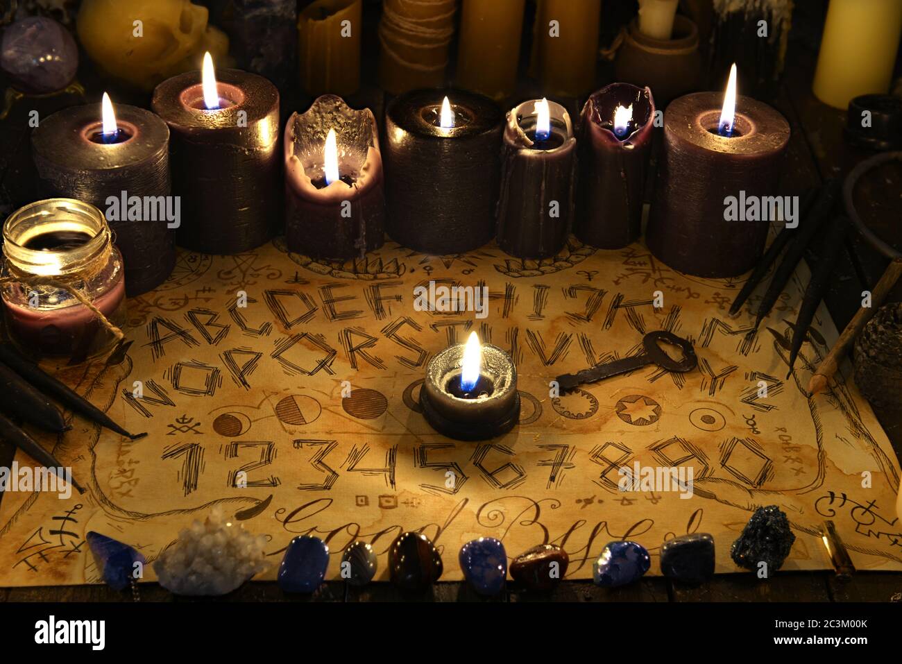 Talking spiritual board with black candles and old key. Wicca, esoteric and occult background with vintage magic objects for mystic rituals. Halloween Stock Photo