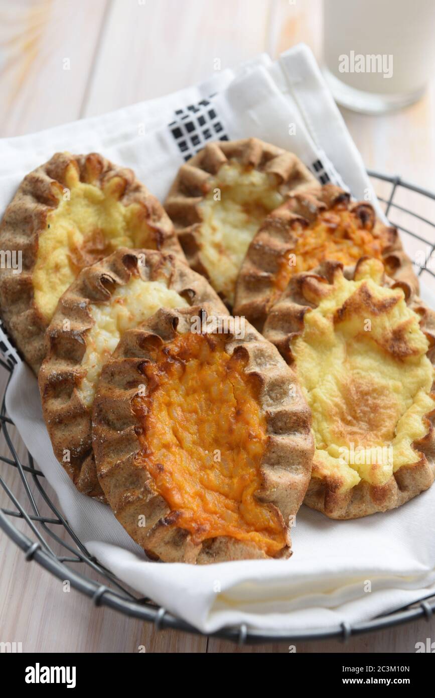 Karelian pasties with potato, carrot, and rice on a rustic table Stock Photo