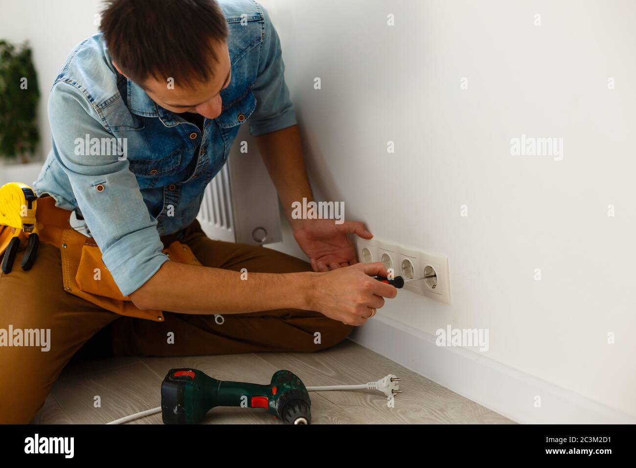 Electrician checking socket voltage with digital multimeter Stock Photo