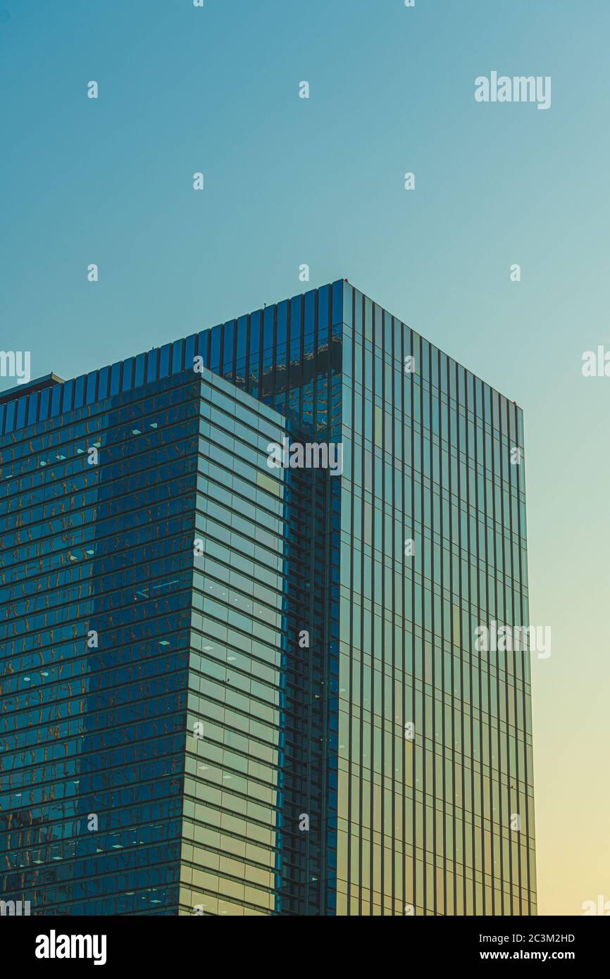 Vertical low angle shot of a glass building under the blue sky captured ...