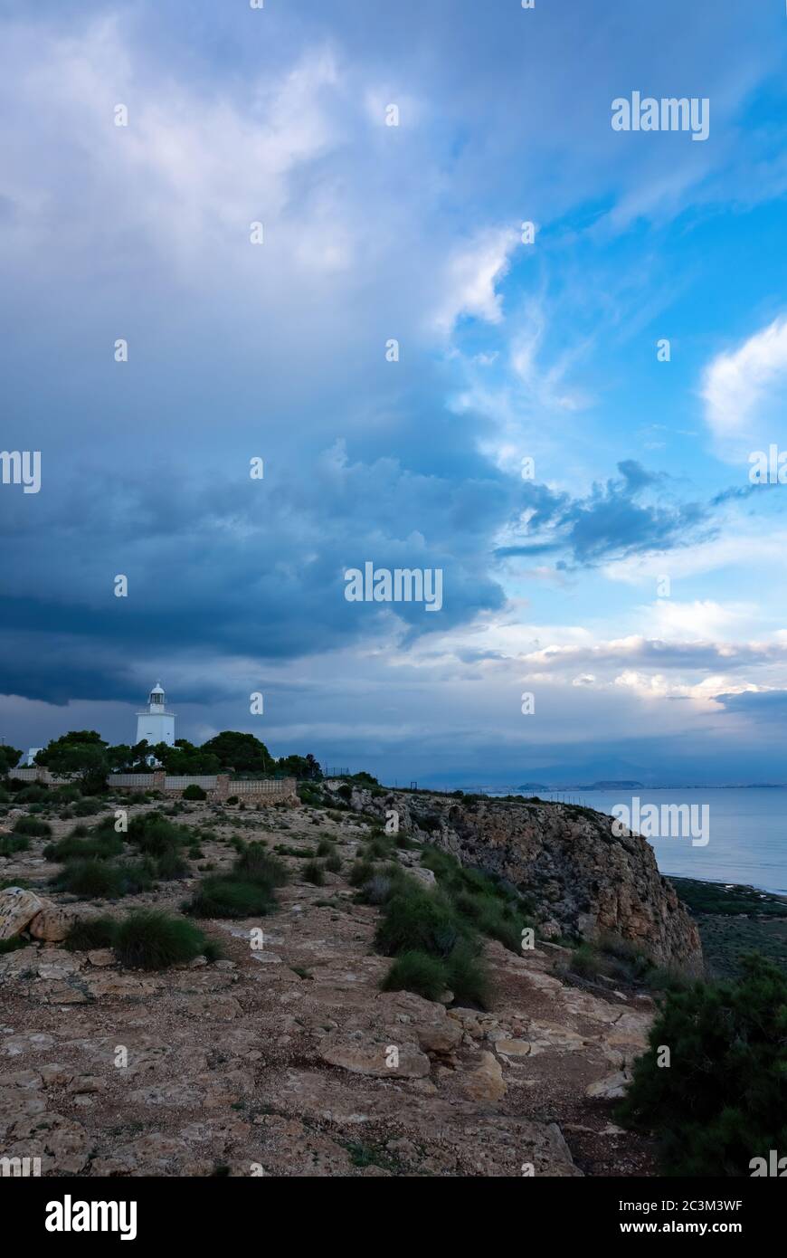 Lighthouse of Santa Pola built in 1858 near Alicante, Spain. Rainy clouds and sea view. Stock Photo