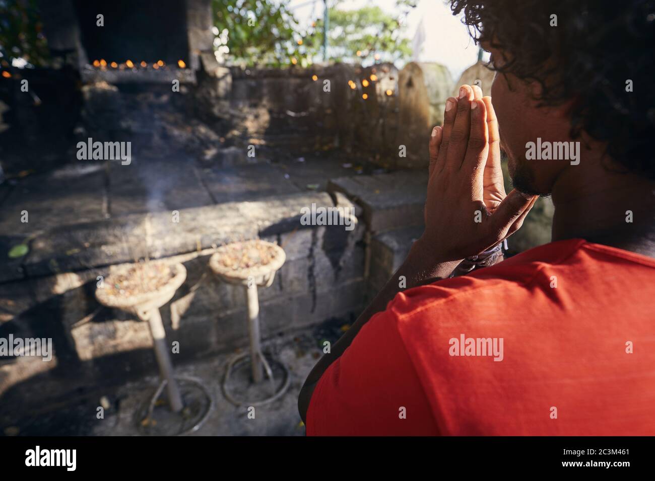 Hands of a praying man.(Buddhist) praying against shrine with incenses. Dambulla, Sri Lanka. Stock Photo