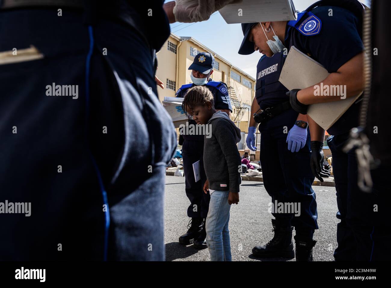 South African metro police crowd an African foreign national child refugee for violating Cape Town's city bye-laws during the coronavirus outbreak Stock Photo