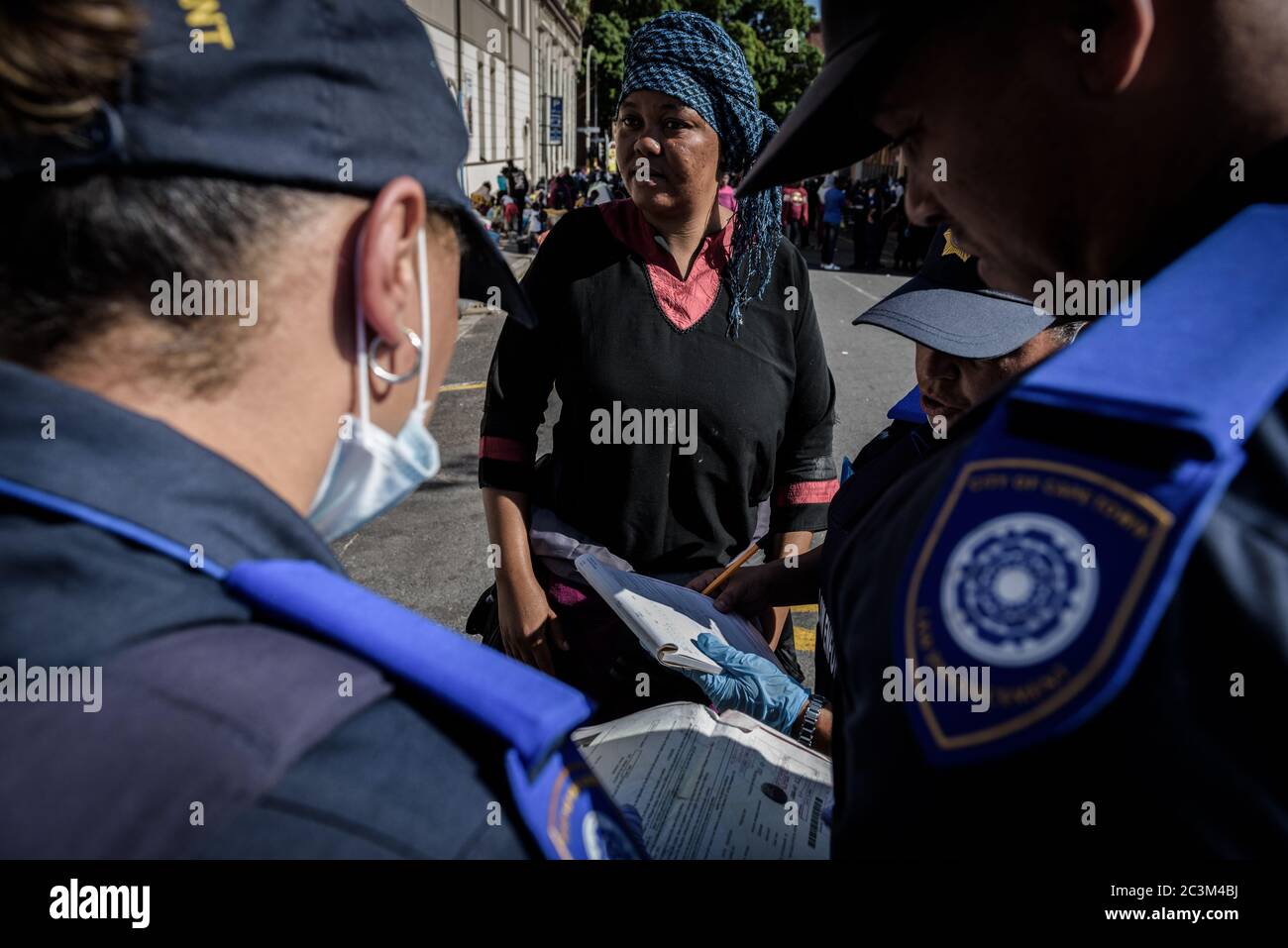 South African police issue fines to homeless African foreign national refugees for violating Cape Town's city bye-laws during the coronavirus outbreak Stock Photo