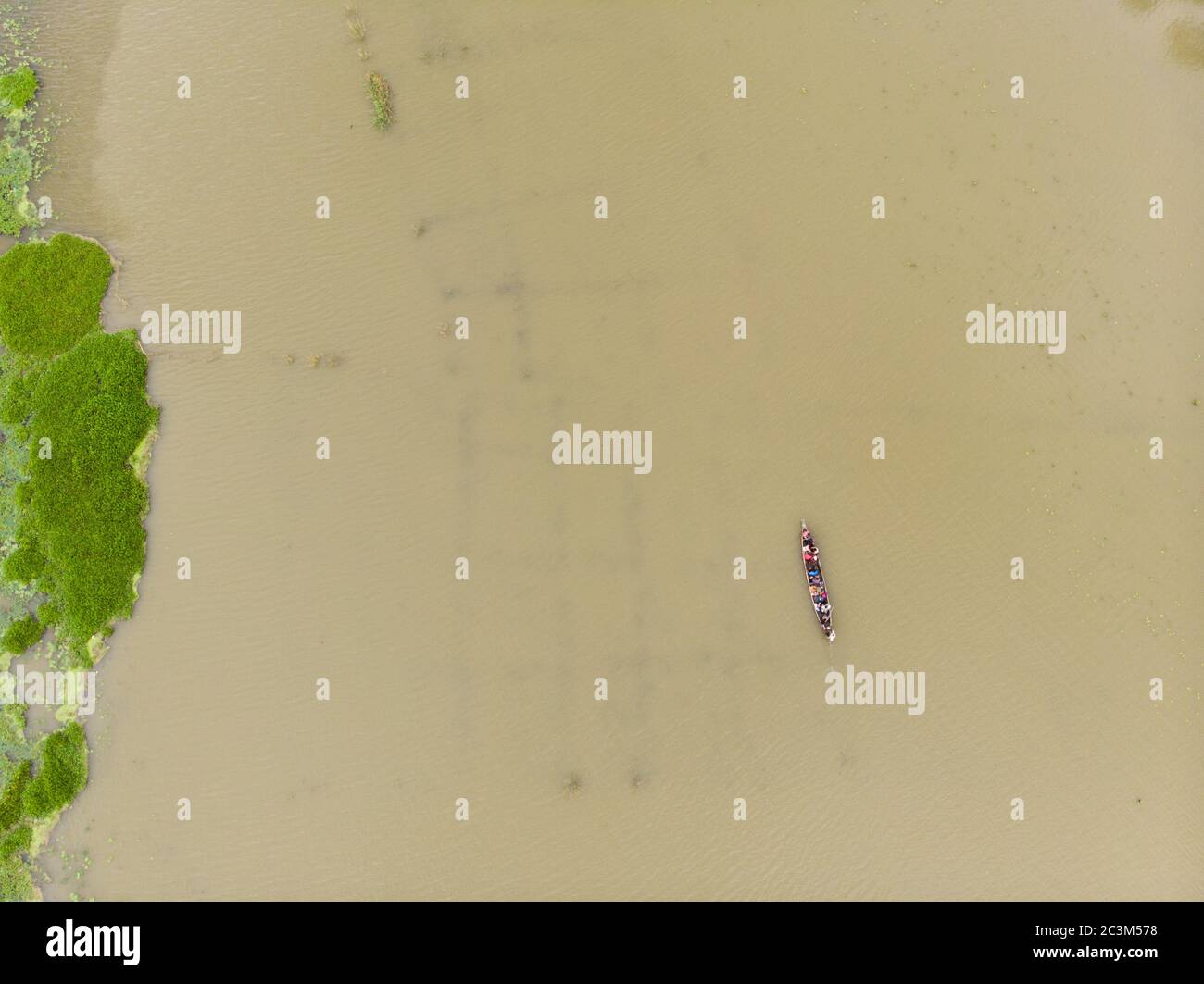 Bird's eye view of a narrow wooden boat full of people sailing in a ...