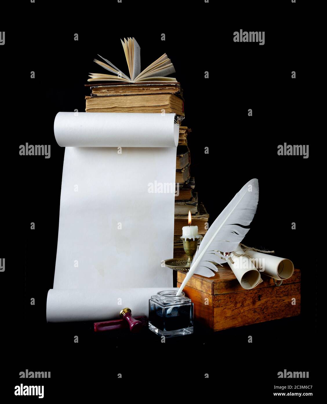 Still life with a letter, a pen, a lighted candle in copper candlestick on a background of old books Stock Photo