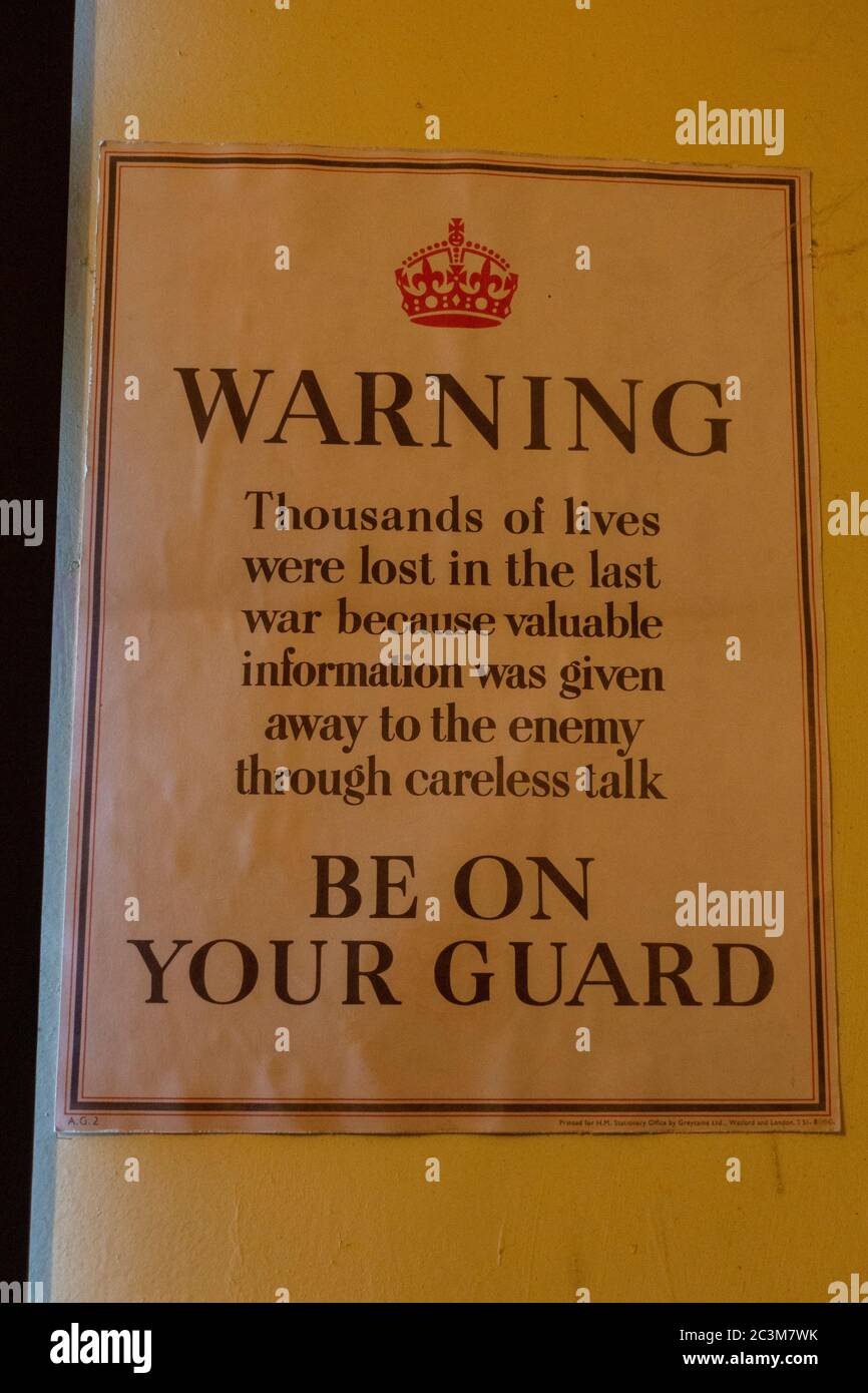 Poster warning workers about careless talk, 'Warning. Be On Your Guard', on display in Bletchley Park, Bletchley. Buckinghamshire, UK. Stock Photo