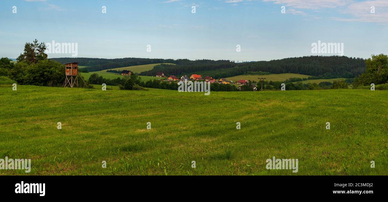 Beautiful rolling landscape scenery above Valaske Prikazy village in Czech republic with meadows, smaller village on valley, hills and hunting stand Stock Photo
