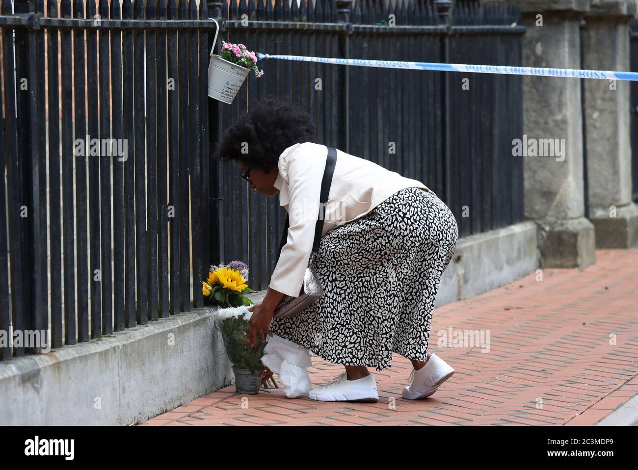 A woman places some flowers at the Abbey gateway of Forbury Gardens in Reading town centre following a multiple stabbing attack in the gardens which took place at around 7pm on Saturday leaving three people dead and another three seriously injured. Stock Photo