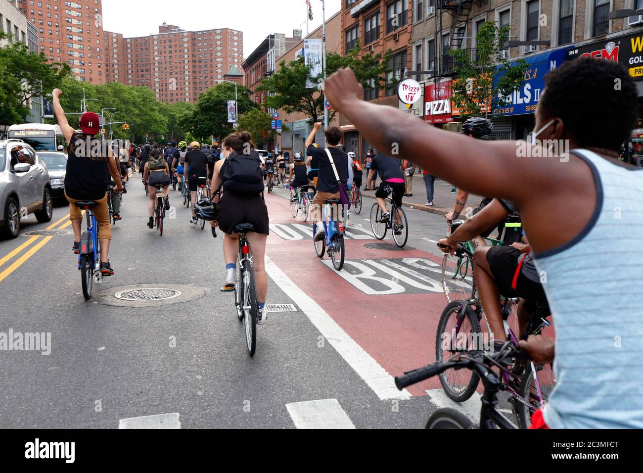 New York, NY. 20th June 2020. Bicyclists raise fists as they ride along  West 125th St. The bike protest was a Black Lives Matter solidarity ride  calling for justice in a recent