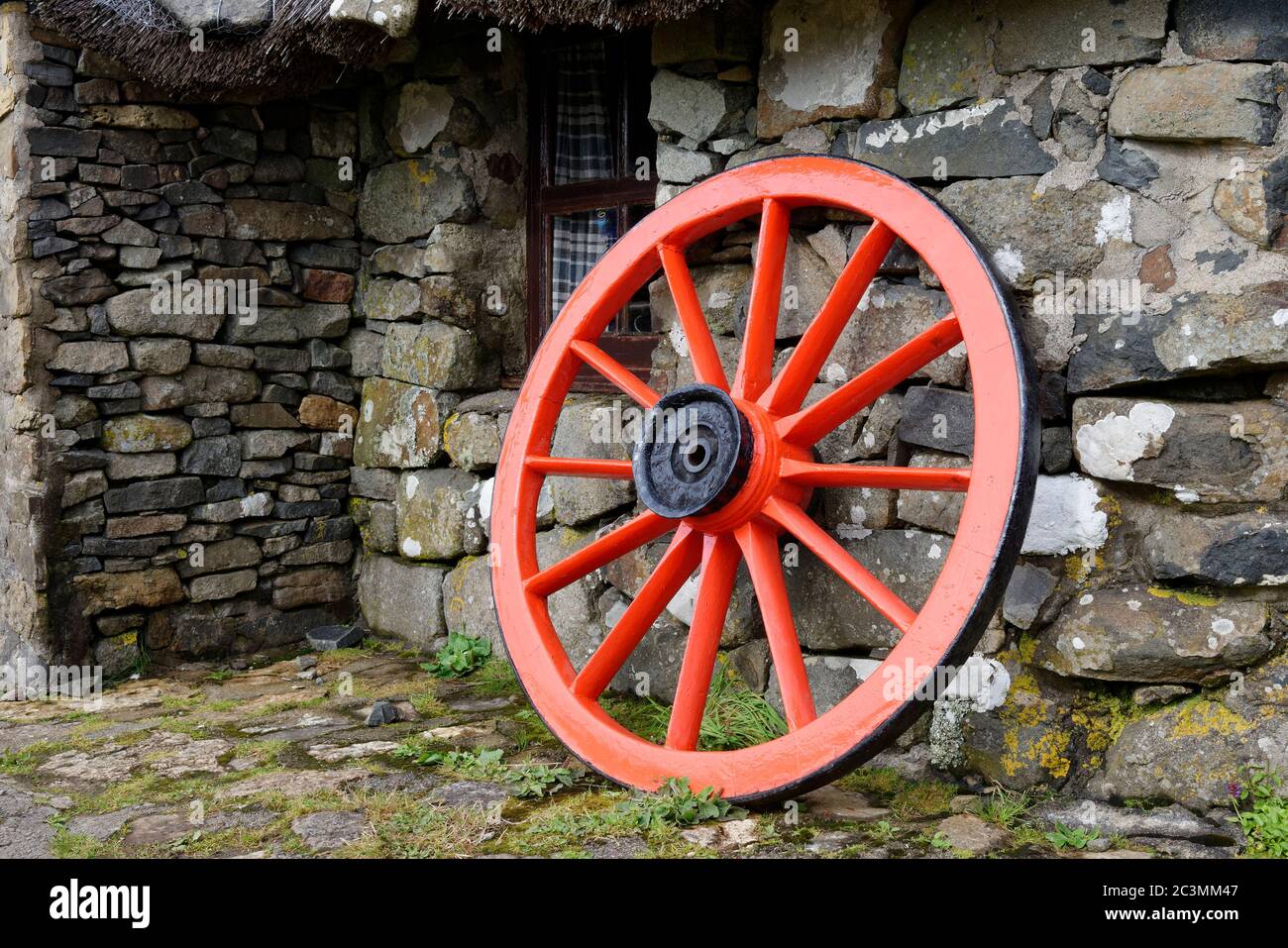 Restored old cart wheel outside Croft Cottage at Skye Museum of Island Life (Osmigarry Croft Museum), Trotternish, Isle of Skye, Scotland, UK Stock Photo