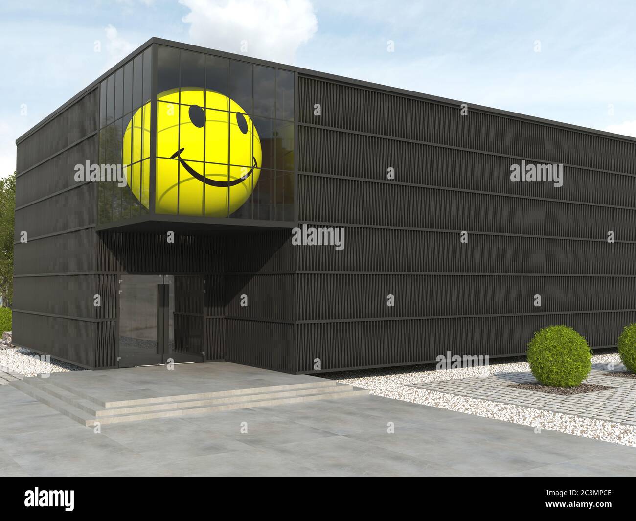 Huge spherical yellow smiley face in the window of a black monochrome building. Large inflated ball in urban architecture. Modern creative facade. Cop Stock Photo