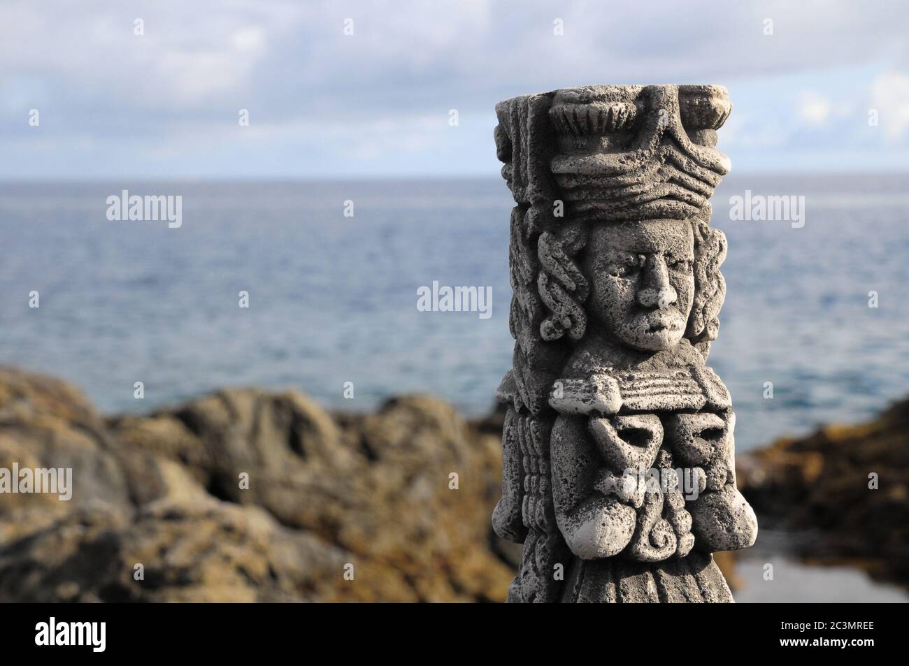 Ancient Maya Statue on the Rocks near the Ocean Stock Photo