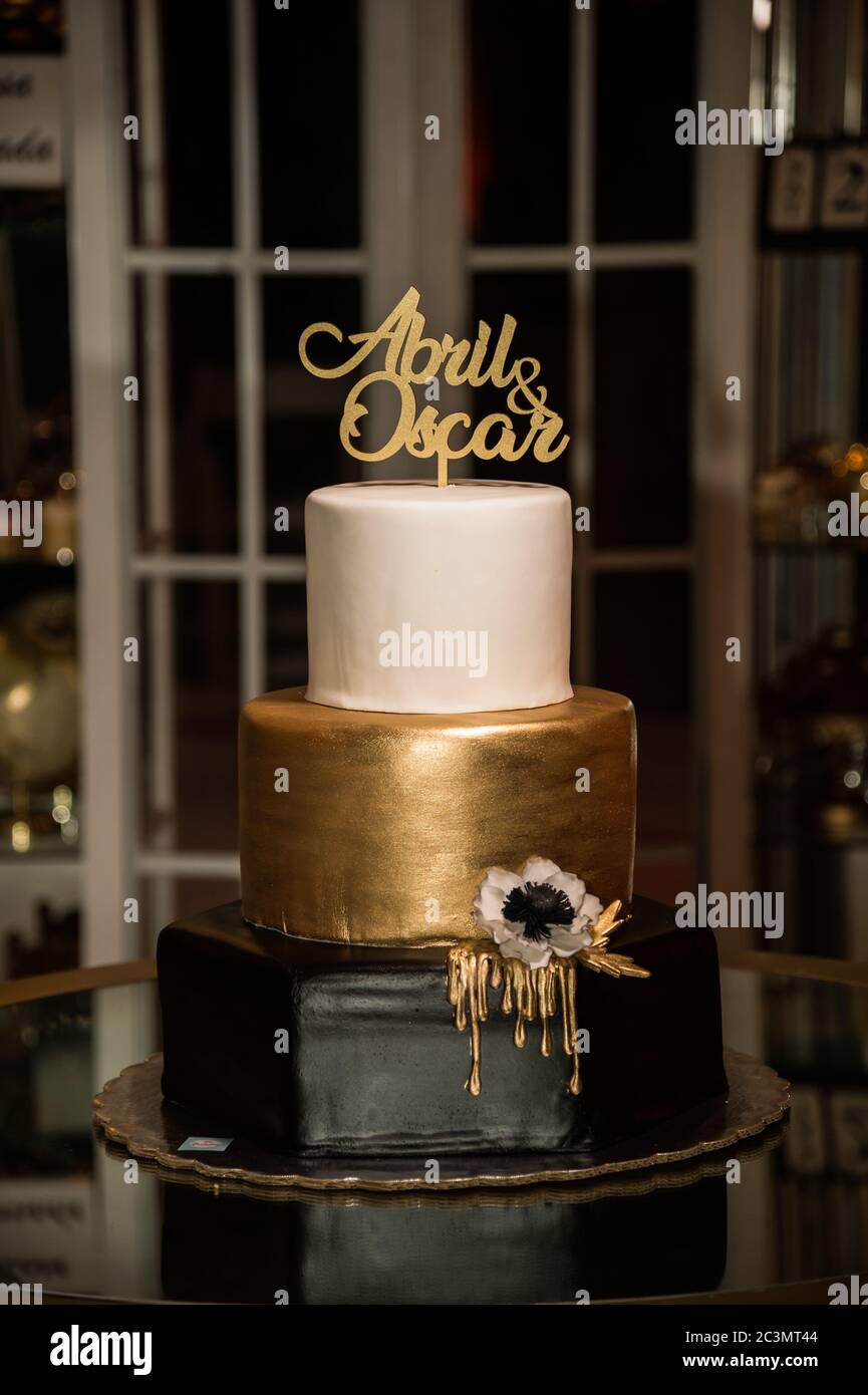 Three Tiered Wedding Cake With Black Gold And White Flowers Topped With The Couple S Names Stock Photo Alamy