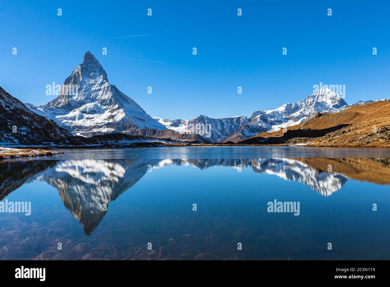 Stunning panorama view of the famous Matterhorn and Weisshorn peak of Swiss Pennine Alps with beautiful reflection in Riffelsee lake on sunny autumn n Stock Photo