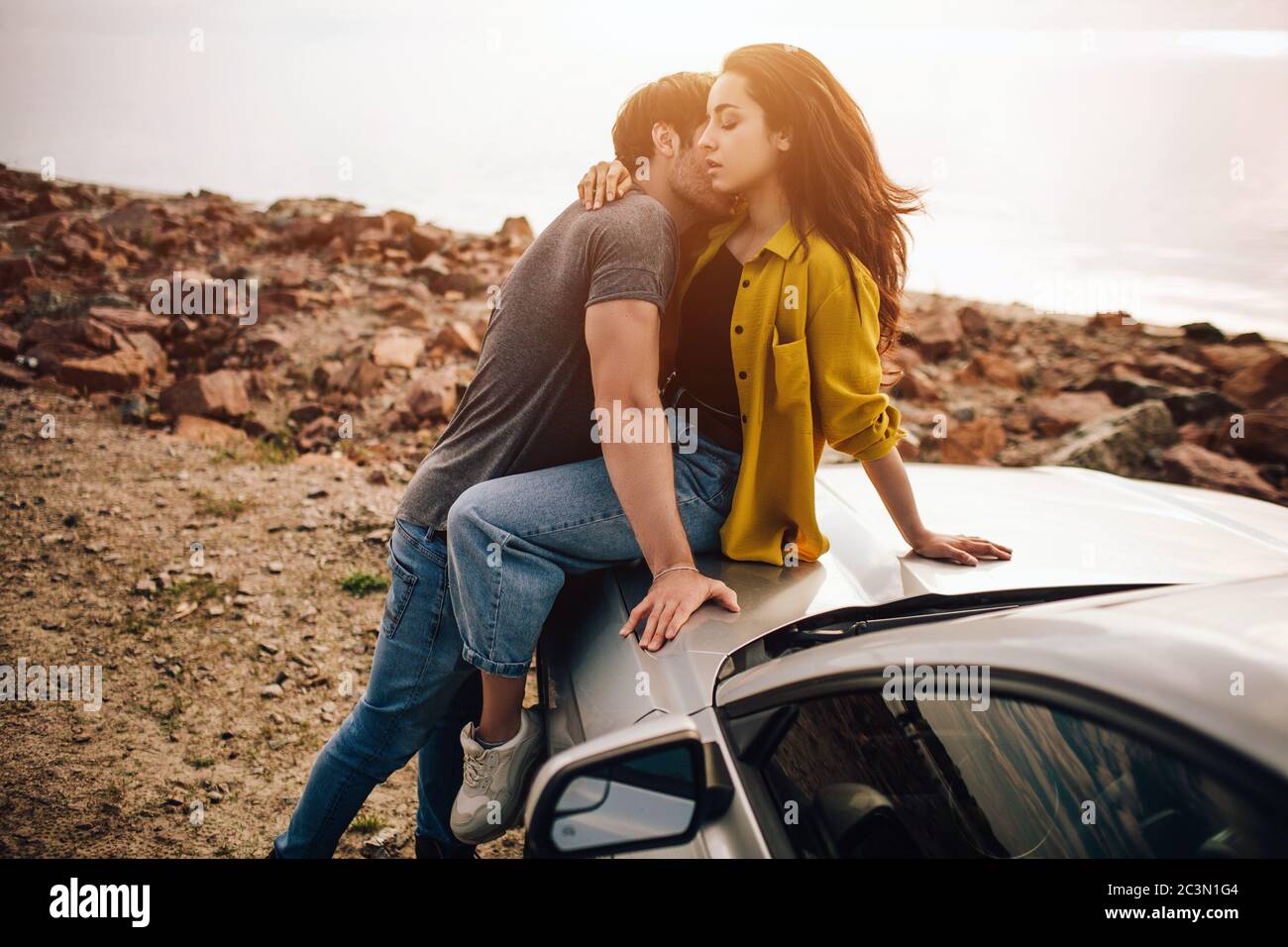 Young Couple Kissing On Bonnet Of Convertible Car High-Res Stock