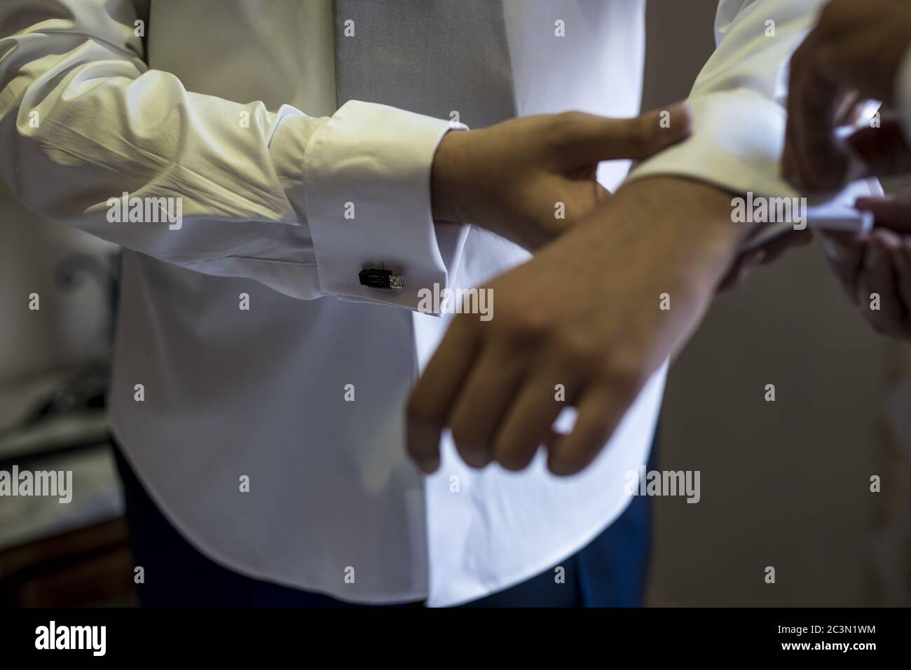 High angle closeup shot of a man in a white shirt adjusting his sleeves Stock Photo