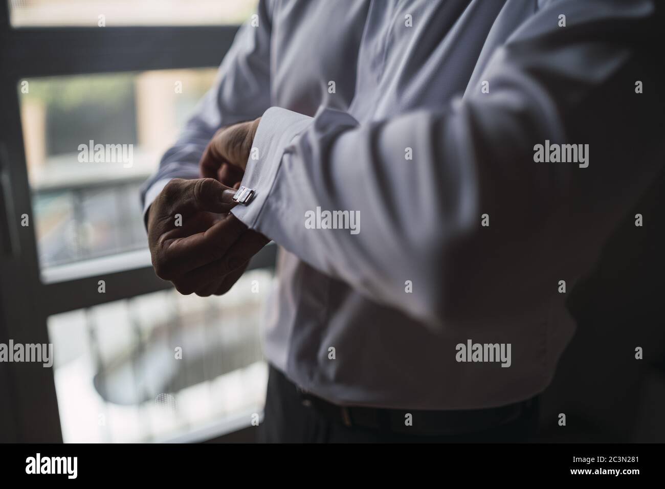 High angle closeup shot of a man in a white shirt adjusting his sleeves Stock Photo