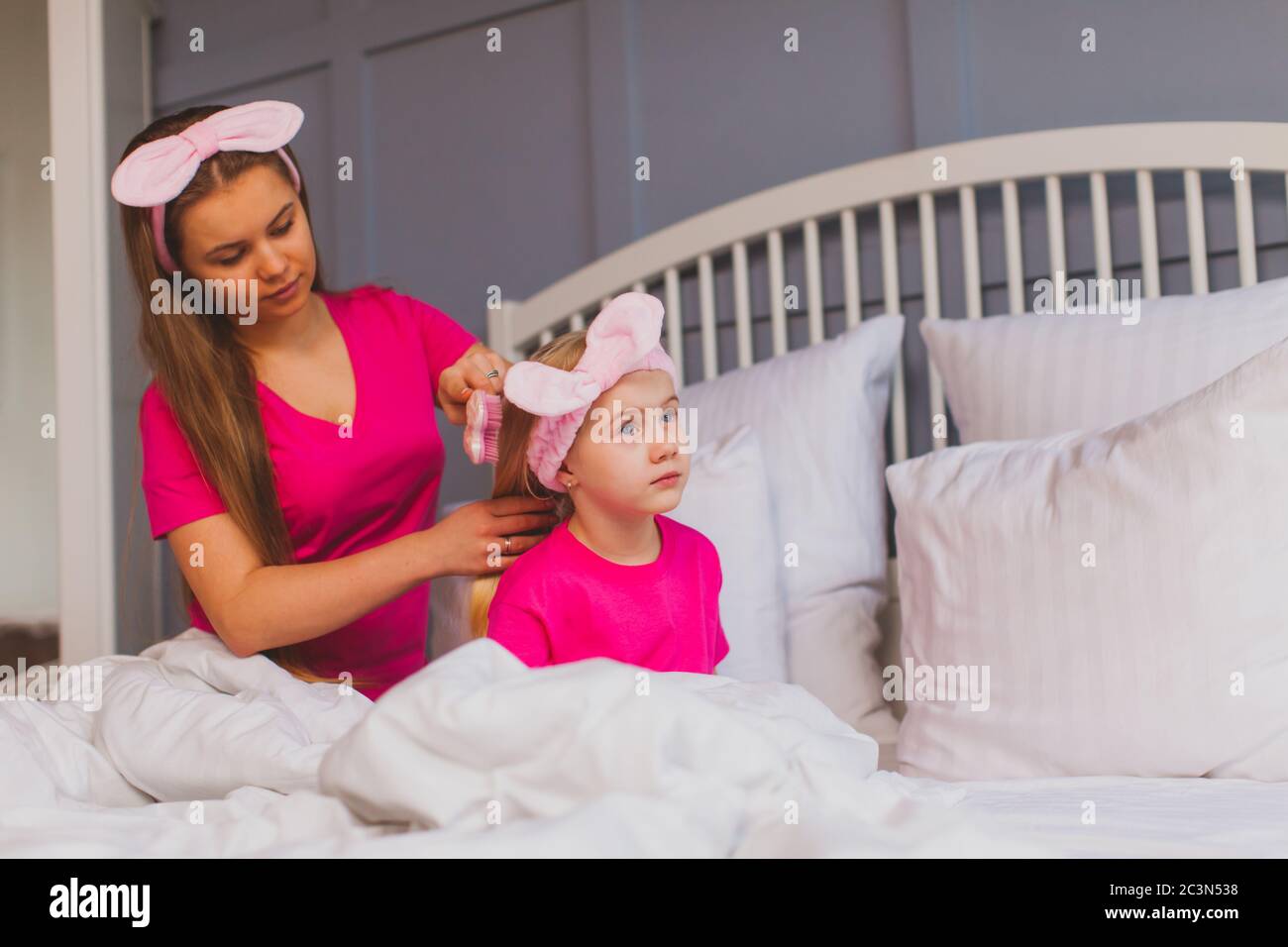 Young mother is combing her little daughters hair Stock Photo