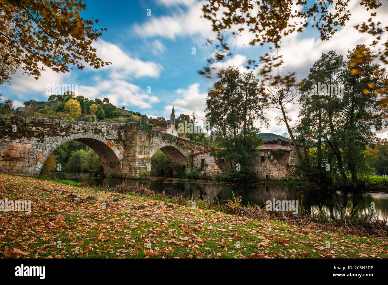 Fall foliage and medieval Roman bridge reflected on the water in the Galician village of Allariz, Ourense. Stock Photo
