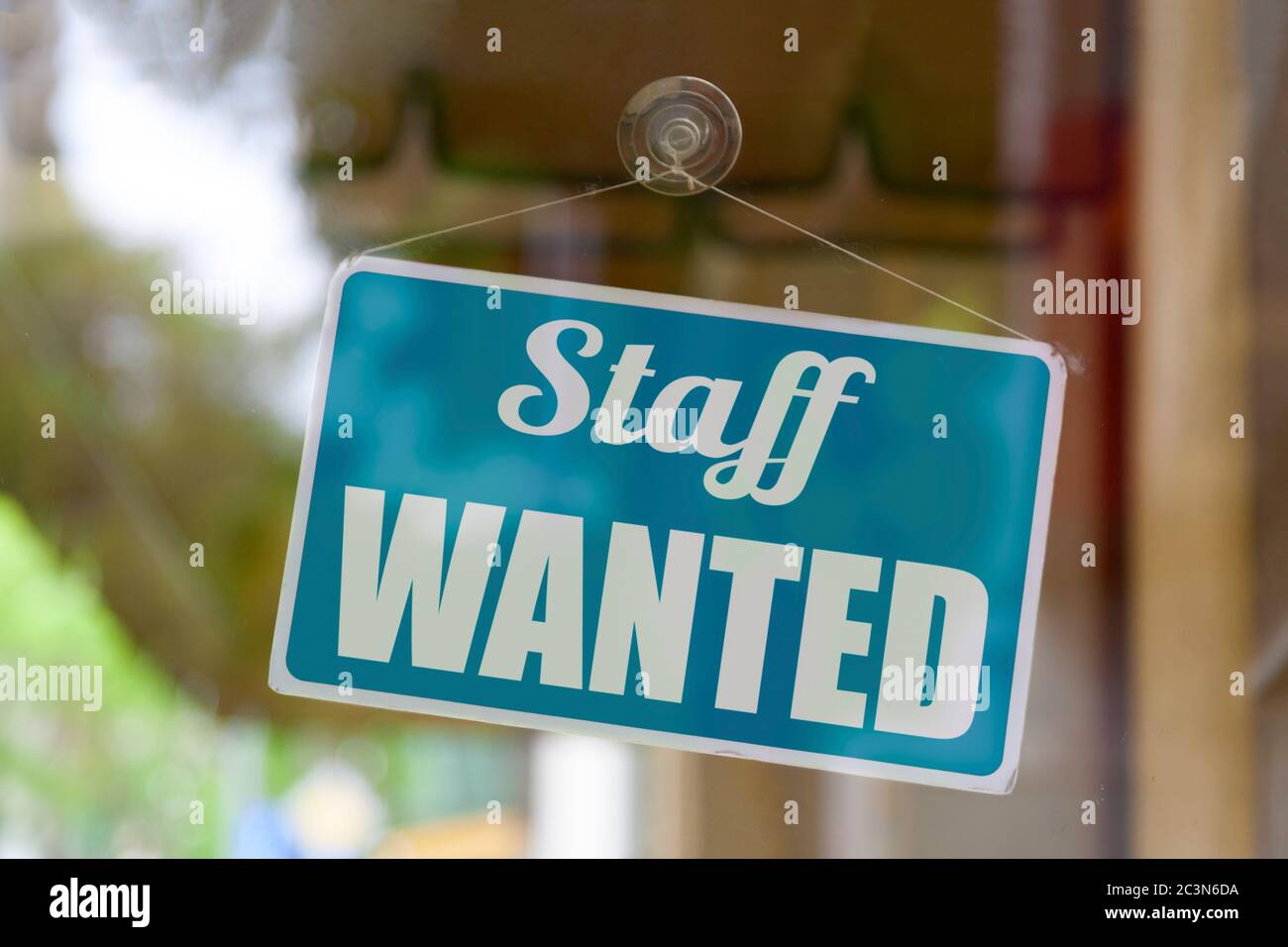 Close-up on a blue open sign in the window of a shop displaying the message: Staff wanted. Stock Photo