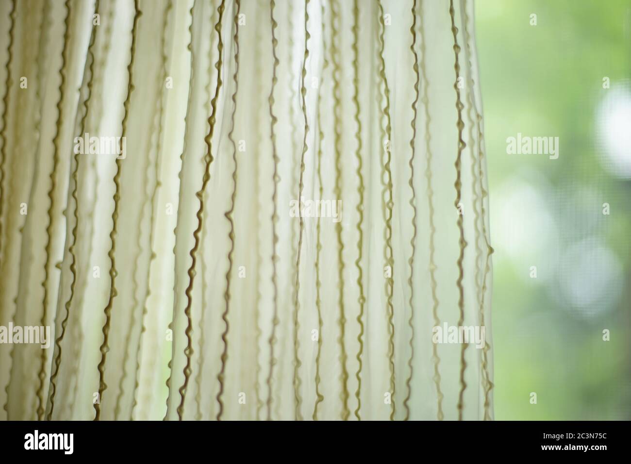 Matte tulle with vertical threads pattern. Green blurred garden in background, front view Stock Photo