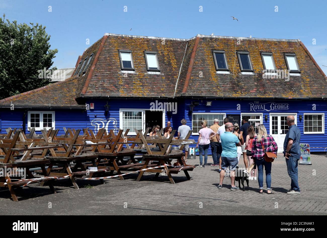 People queue for drinks in the beer garden of the Royal George pub in Folkestone Kent. Stock Photo