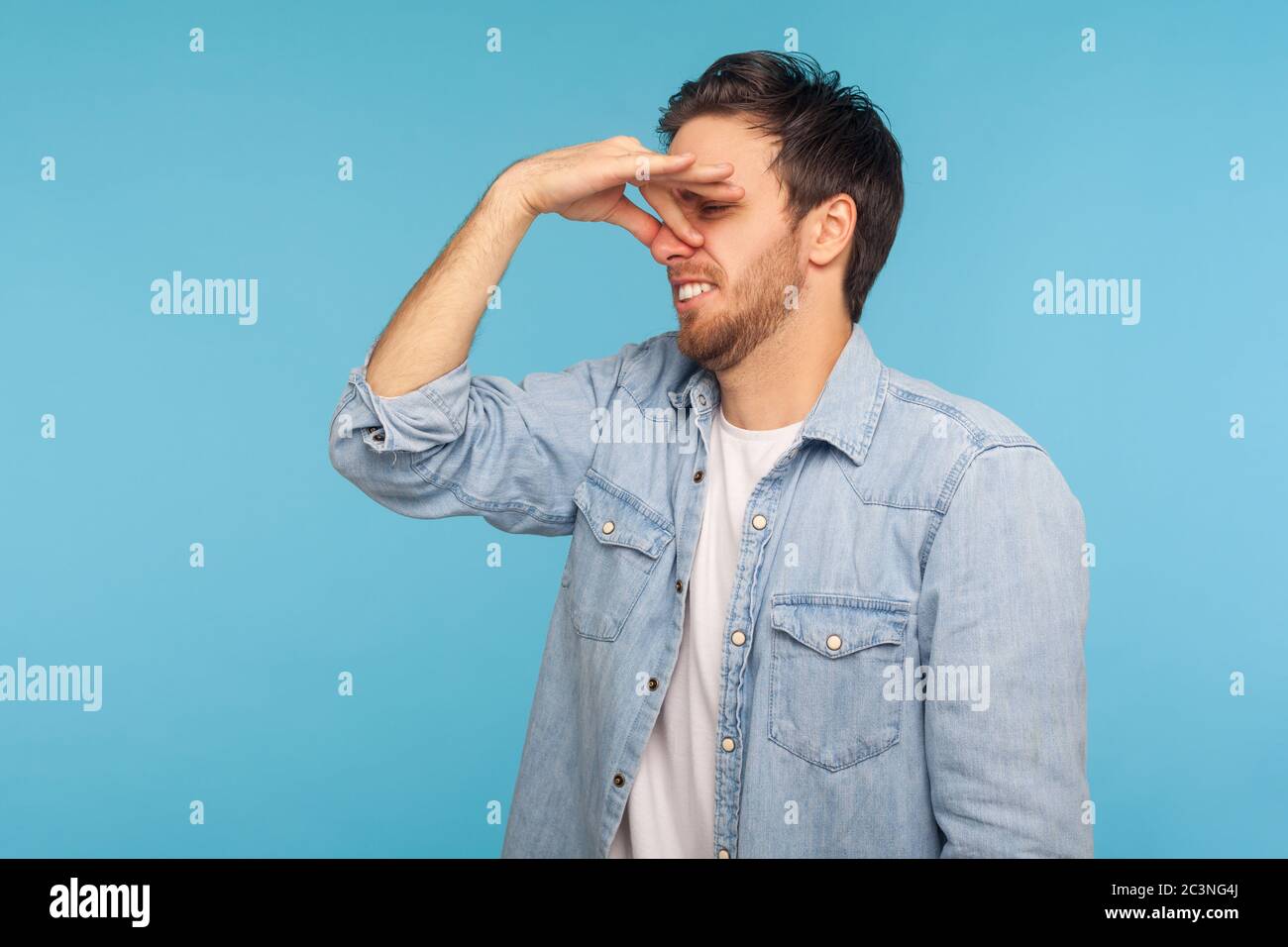 Awful stink! Portrait of man in worker denim shirt grimacing in disgust