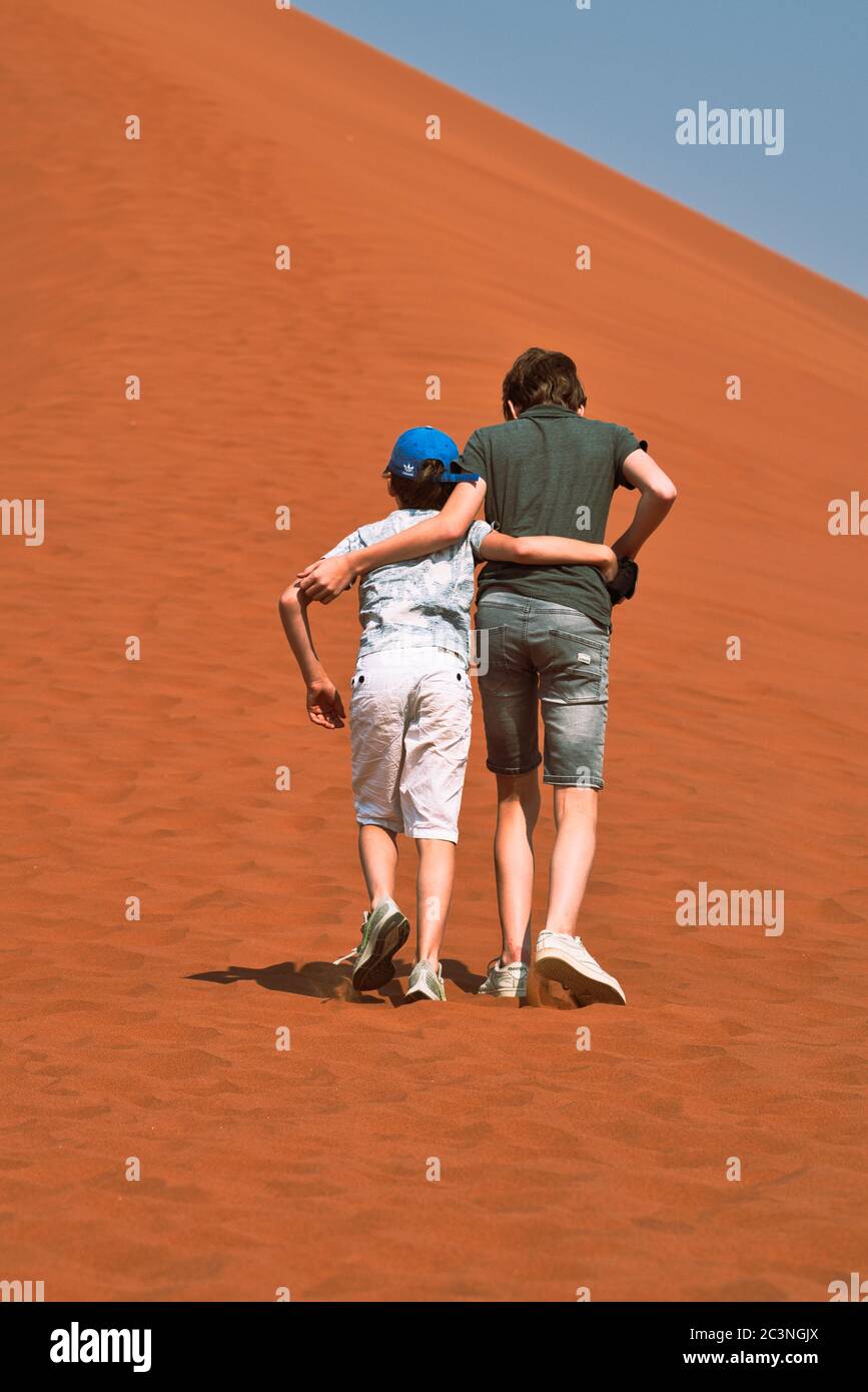 2 Brothers climbing a sand dune in Namibia Stock Photo