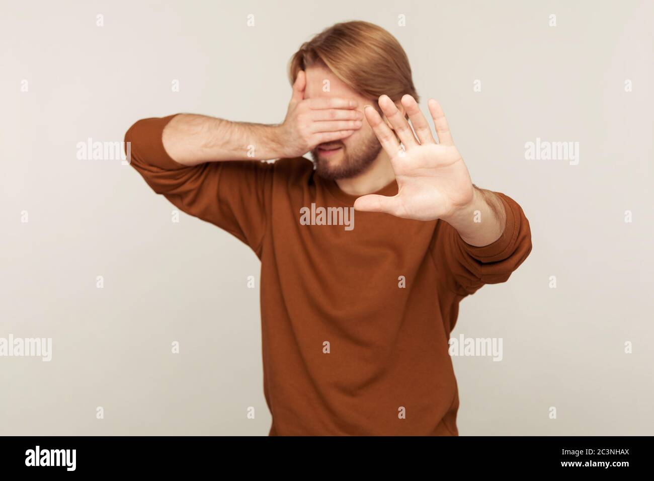 No, don't want to look! Portrait of confused man covering eyes and ...