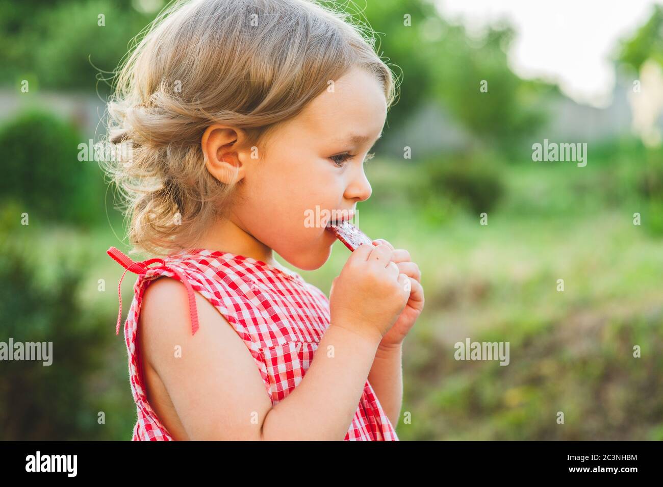 Girl Eating Sausage At Family Barbeque. 2 years old girl eats sausage