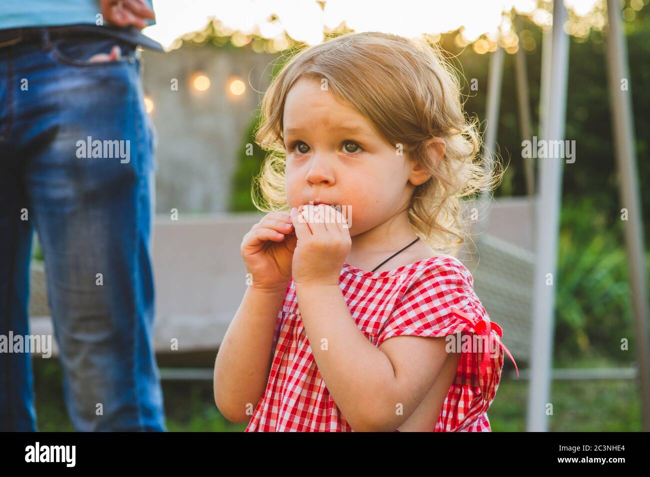 Girl Eating Sausage At Family Barbeque. 2 years old girl eats sausage