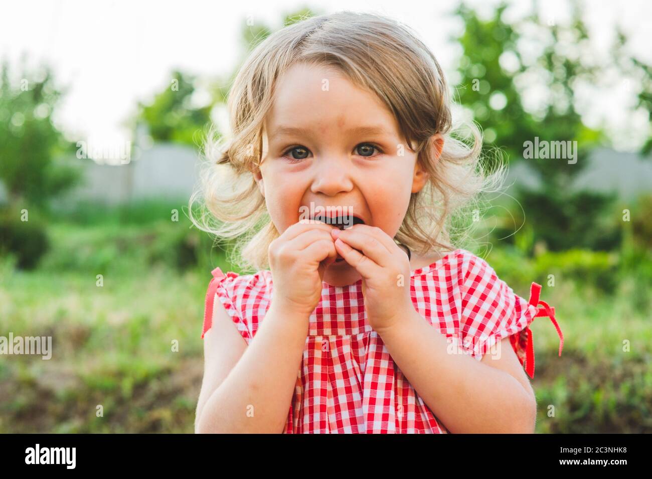 Girl Eating Sausage At Family Barbeque. 2 years old girl eats sausage